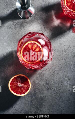 Negroni cocktail with ice cubes and blood orange on a dark gray stone background, top view. Stock Photo