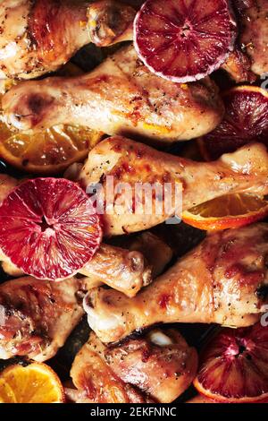 Spice roasted chicken drumstick in roasting pan. Baked chicken legs with oranges. Stock Photo