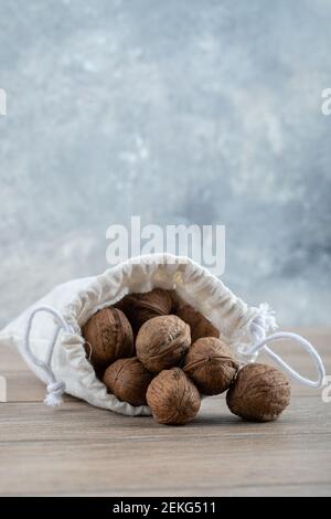 A white sack full of walnuts on a wooden table Stock Photo