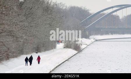 Brunswick, Germany. 12th Feb, 2021. Strollers walk along the frozen Mittellandkanal near the port of Braunschweig. Numerous ships have been moored for several days in the inland port of the former Hanseatic city because the Mittelland Canal has frozen over; all icebreakers have been recalled to keep the Weser free of ice. Credit: Stefan Jaitner/dpa/Alamy Live News Stock Photo