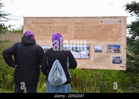 Indigenous residential schools survivors look at billboards displayed on the location of where the residential school on Fort George Island , James Bay, Northern Quebec Canada Stock Photo