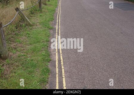 Double yellow lines on a narrow country lane, meaning no parking is allowed Stock Photo