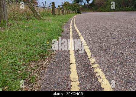 Close up of double yellow lines on a narrow country lane, meaning no parking is allowed Stock Photo