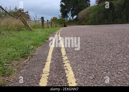 Low level close up of double yellow lines on a narrow country lane, meaning no parking is allowed Stock Photo