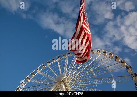WA19314-00...WASHINGTON - The Seattle Great Wheel and the American flag located on Pier 57, Miner's Landing, on Elliott Bay in Seattle. Stock Photo