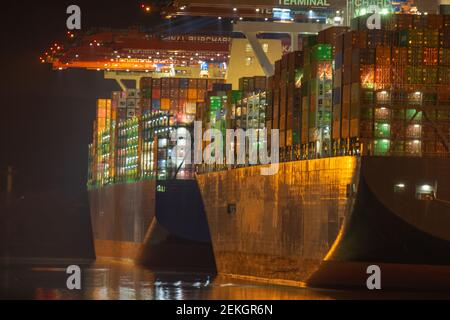 Two Container vessel ship in port quayside during loading process at night in a row Stock Photo
