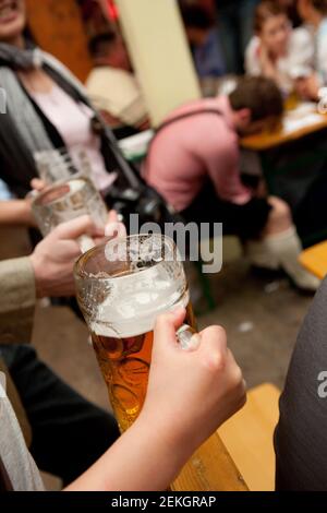 Revelers celebrate Octoberfest (Oktoberfest) inside the tents on Theresienwiese. Another drunken reveler (out of focus) has passed out on the table, Stock Photo