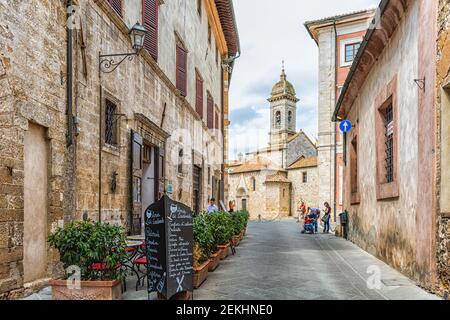San Quirico D'Orcia, Italy - August 26, 2018: Street road historic medieval town village in Tuscany and famous church bell tower with menu for Osteria Stock Photo