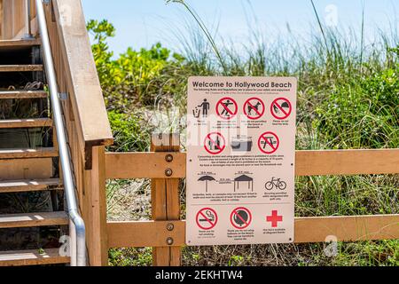 Hollywood, USA - May 6, 2018: Beach boardwalk in Miami, Florida with wooden steps stairs and welcome entrance sign with rules and prohobited activitie Stock Photo