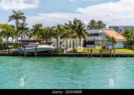 Bal Harbour, USA - May 8, 2018: Wealthy rich single family home house with dock and boat docked by waterfront in Miami Florida with light green turquo Stock Photo