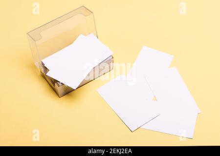 Personal presentation accessory in close up. Business contacts concept. Business cards stack in card holder on yellow background. Name cards in white color with copy space. Stock Photo