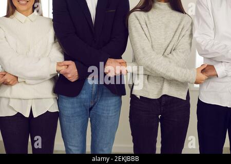 Company workers standing in row and holding hands, showing unity and team spirit Stock Photo
