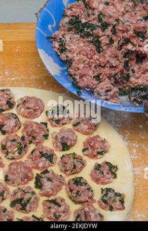 Cooking at home. Form for sculpting dumplings. Dough and minced meat with spinach. Close-up, selective focus. Stock Photo