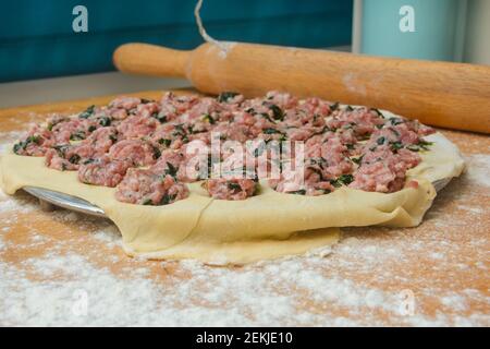 Cooking dumplings in iron round form. Minced meat with spinach on thin crust. Close-up, selective focus, blur. Stock Photo