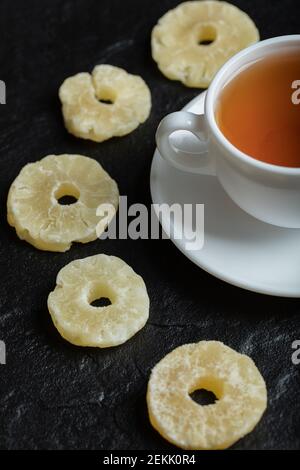 A cup of aroma tea with dried pineapple on a dark background Stock Photo