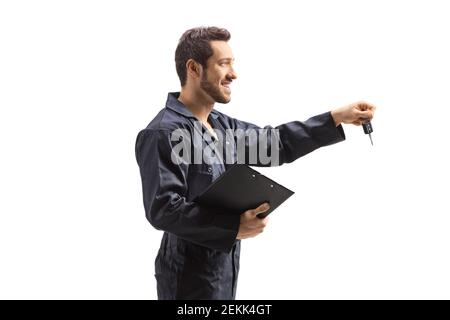 Mechanic in overalls holding a clipboard and car keys isolated on white background Stock Photo