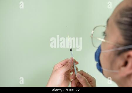 Hispanic female doctor preparing injection to vaccinate Stock Photo