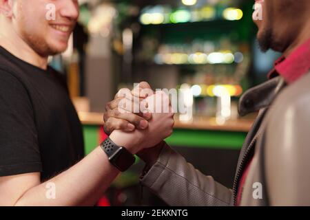 Close-up of young men greeting each other during their meeting in the pub Stock Photo