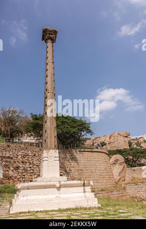 Chitradurga, Karnataka, India - November 10, 2013: Fort or Elusuttina Kote. Tall beige Victory pillar closeup near Ekanatheshwari Temple with green tr Stock Photo