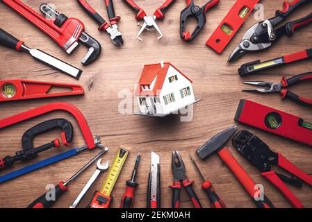 Assorted work tools and house on wooden background Stock Photo