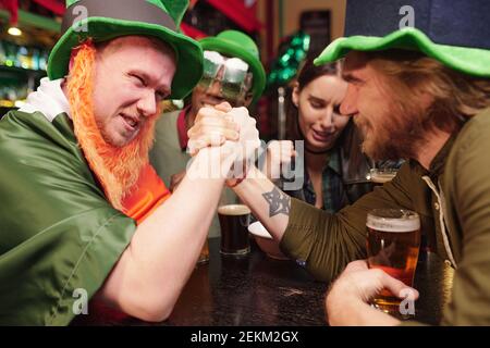 A young man holds hands and competing with each other during an arm wrestling match at a table in a bar Stock Photo