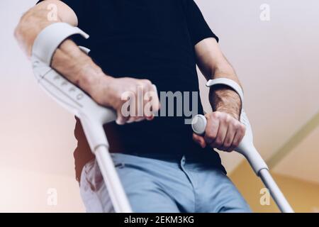 Disabled young man using crutches to walk. Stock Photo