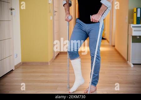Disabled young man using crutches to walk. Stock Photo