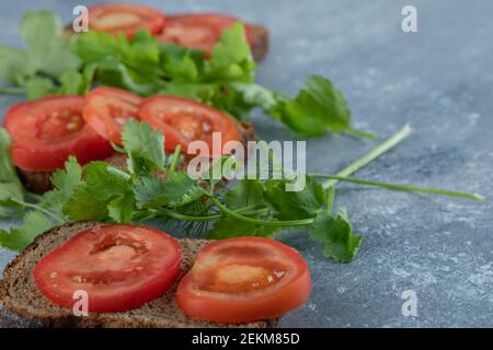 Delicious toasts with slices of tomato on a gray background Stock Photo