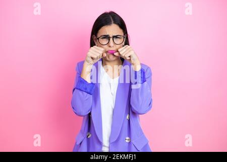 Young business woman wearing purple jacket over pink background depressed and worry for distress, crying angry and afraid. Sad expression. Stock Photo