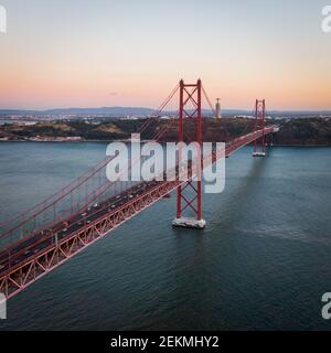 Aerial view of traffic on the 25 de Abril Bridge over the Tagus River at sunset in Lisbon, Portugal.