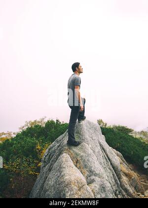 Epic adventure of brave and ambitious hiker trekking activity on wild cliff, pose with panoramic nature mountain landscape. Winner motivation and Stock Photo