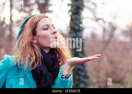 Young redhead Caucasian woman sending kisses at early spring Stock Photo