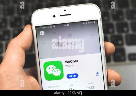 Kharkov, Ukraine - February 22, 2021: man holding smartphone with Wechat application in App Store on Apple iPhone screen, close up photo Stock Photo