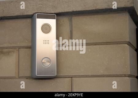 Silver intercom panel with video camera on a brick beige fence pillar of a private house Stock Photo