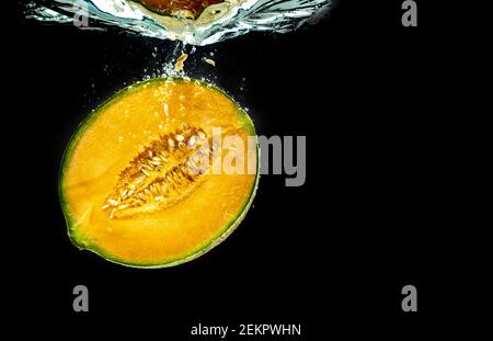 Half of Orange cantaloupe melon sinking and isolated on black background Stock Photo