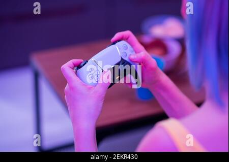 Girl with next gen controller in her hands playing games at home. Stock Photo