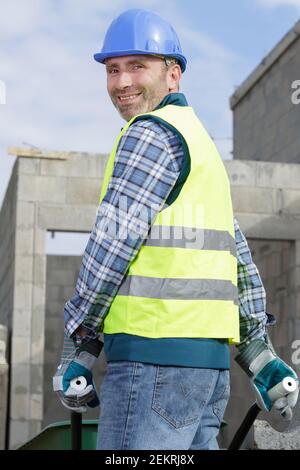 happy construction worker pushing a wheelbarrow Stock Photo