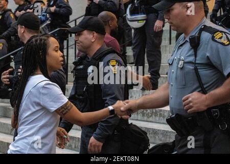 Mia Wells, 19, of Columbus, Ohio shakes Ohio State Trooper’s hand on the steps of the Ohio Statehouse. Wells was deeply moved by the State Troopers’ gesture to take a knee in honor of those killed by racism and police brutality.Large groups of protestors gathered in front of the Ohio Statehouse to protest against police brutality, and the killing of George Floyd by Minneapolis Police Officer Derek Chauvin on May 25, 2020. People protested from 5pm to 10:30pm when the protesters were dispersed by the Riot Police for breaking the 10pm curfew. The day of protest involved marked moments of marchin Stock Photo