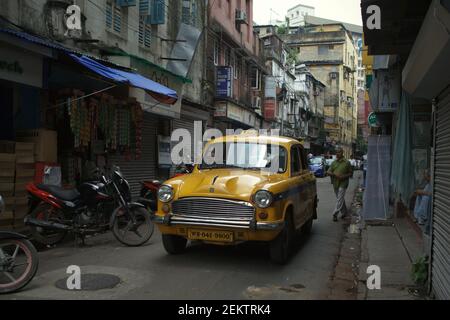 A yellow cab moving through a narrow street in Kolkata, West Bengal, India (2013).  Kolkata's yellow taxis are lately 'hardly visible on the streets' of the city, according to a publication by 'Kolkata on Wheels', a monthly motoring and lifestyle magazine. Stock Photo