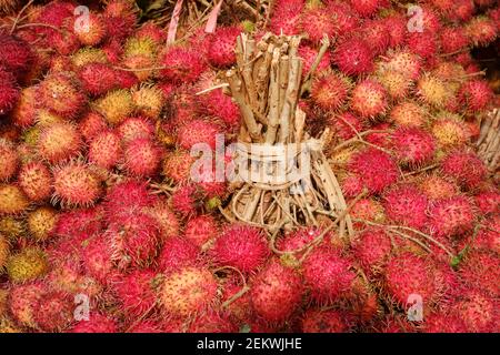 Rambutan skin texture in traditional fruit markets. a fresh red rind pattern with a tied stalk. Rambutan is a tropical plant belonging to the Sapindac Stock Photo