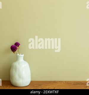 Vase of purple globe amaranth flowers on wooden table. khaki green background. copy space Stock Photo