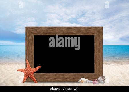 Wooden picture frame with copy space on blurred summer sandy beach, blue sea and sky background with starfish and seashells. Stock Photo
