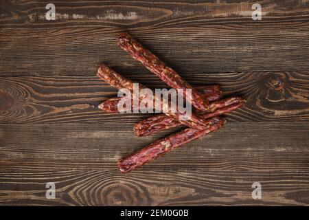 Overhead view of dried jerked deer and pork sausage on wooden background Stock Photo