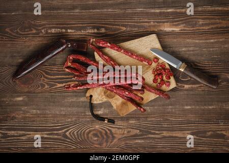 Overhead view of air dried deer and pork sausage on wooden background Stock Photo