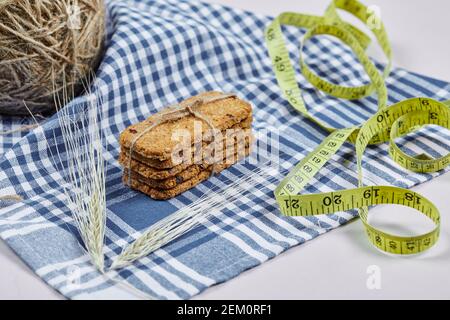 Biscuits and tape measure on a white background with tablecloth, close up Stock Photo