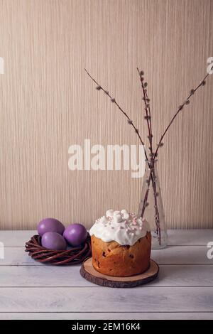 Easter cakes decorated with marshmallows and painted Easter eggs in a wicker nest with willow on a light background. Stock Photo