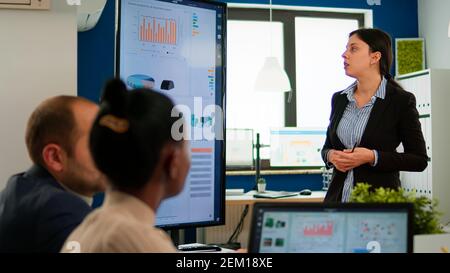 Professional entrepreneur discussing about project with her collegues, explaning company strategy during brainstorming. Diverse team working in professional startup financial office during conference Stock Photo