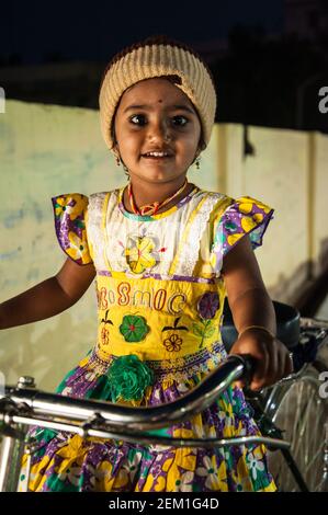 Gudur, Andhra Pradesh, India: Young Indian girl wearing a colorful dress on bicycle ride in evening. Stock Photo