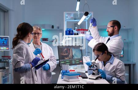 Team of scientific investigators conducting experiments in lab using microscope and micropipette. Laboratory for disease research with professional equipment for virus study and diagnosis development Stock Photo