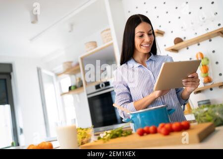 Happy beautiful woman learning to cook with online course at home Stock Photo